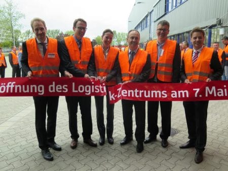 Fünf Männer und eine Frau mit orangenen Westen beim Durchreißen eines Banners